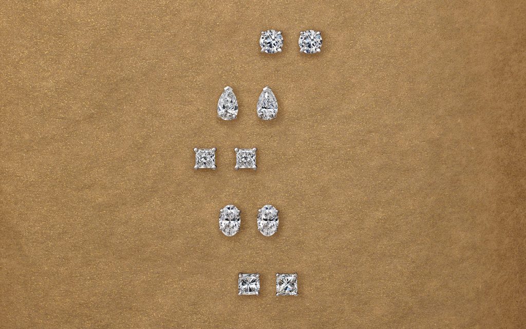 Five pairs of diamond stud earrings of various shapes such as princess, oval, round and pear.